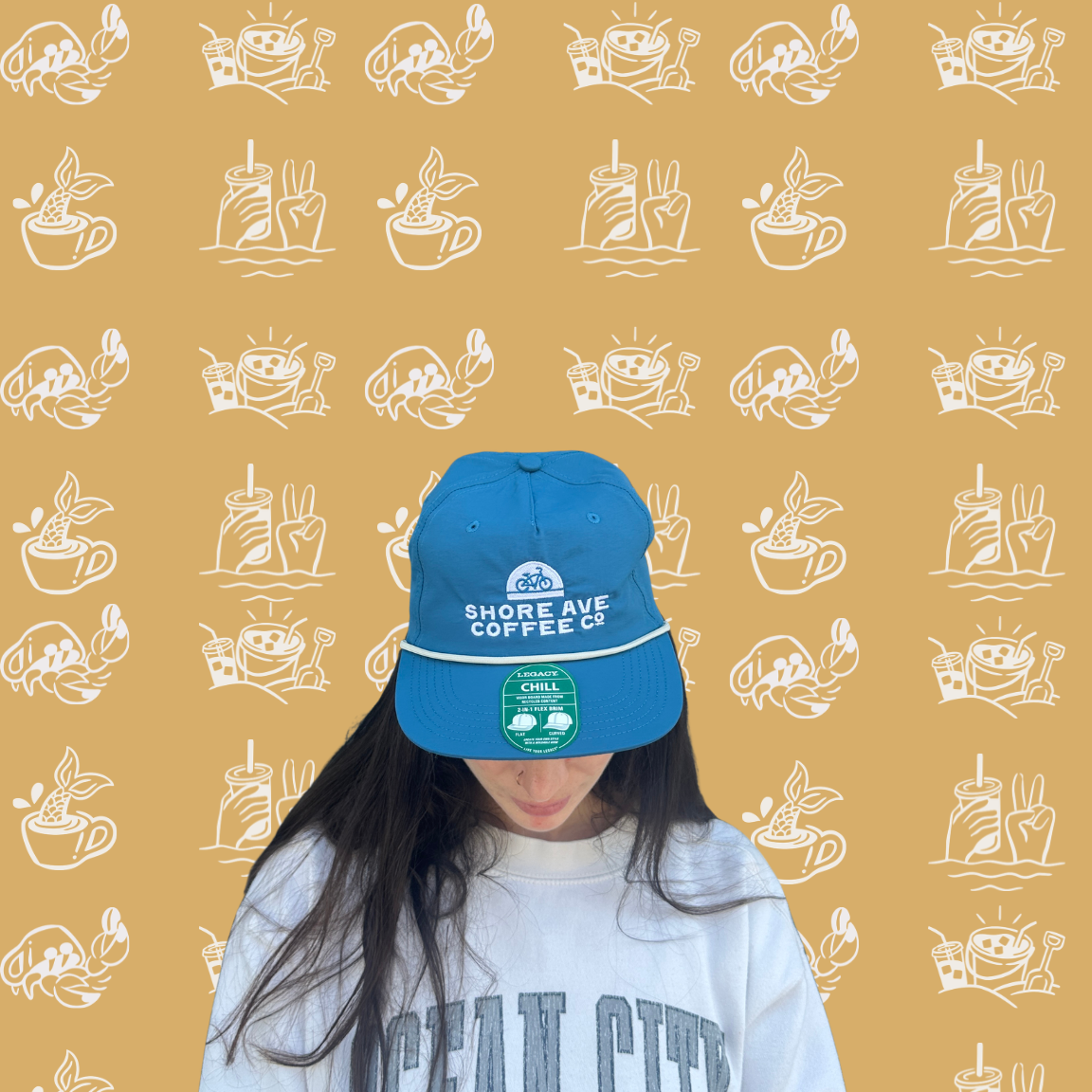 Person wearing a blue cap and white sweatshirt with 'Ocean City' text on a patterned yellow background